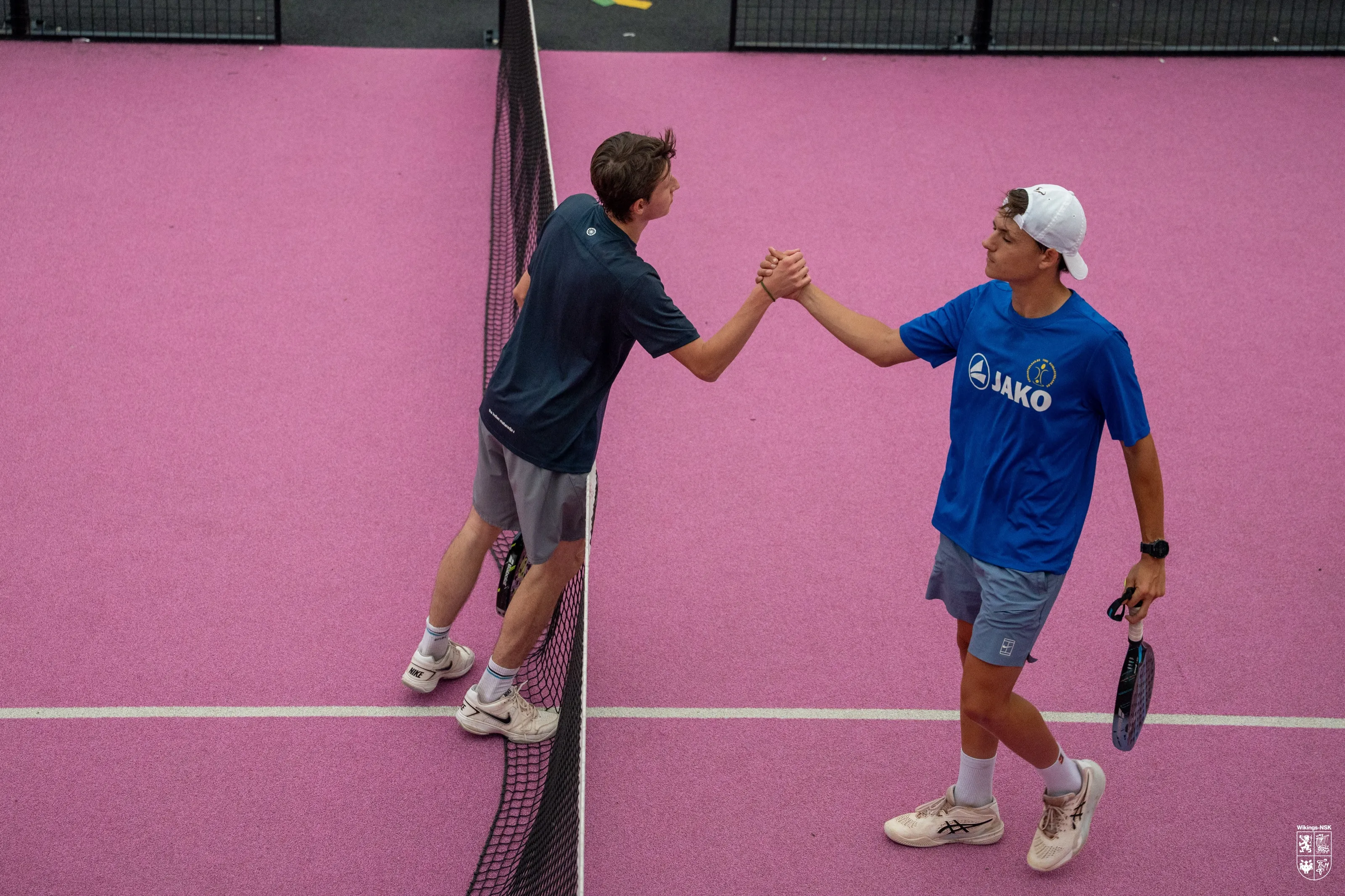 Twee padelspelers geven elkaar een hand over het net