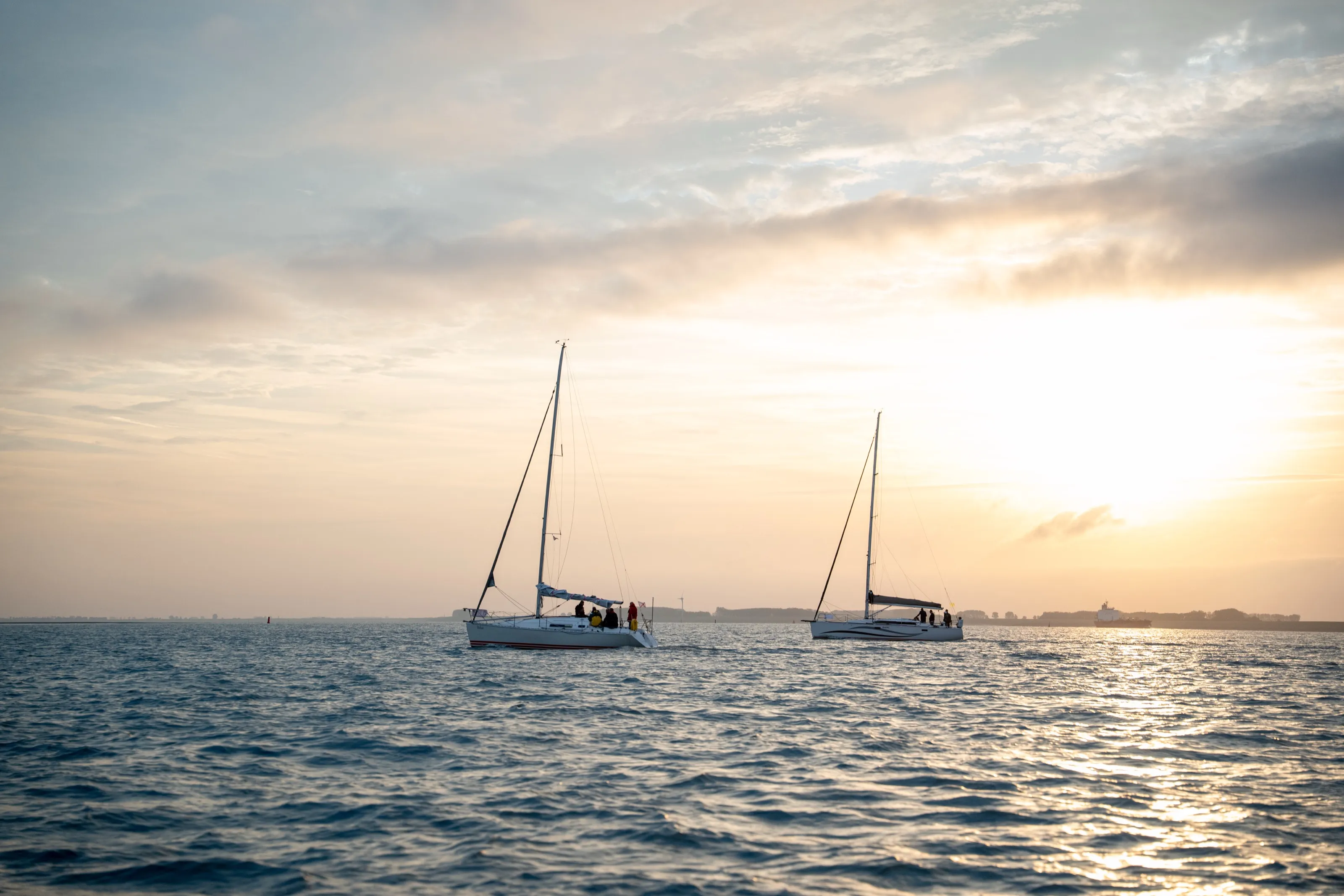 Twee zeilboten op zee bij zonsondergang