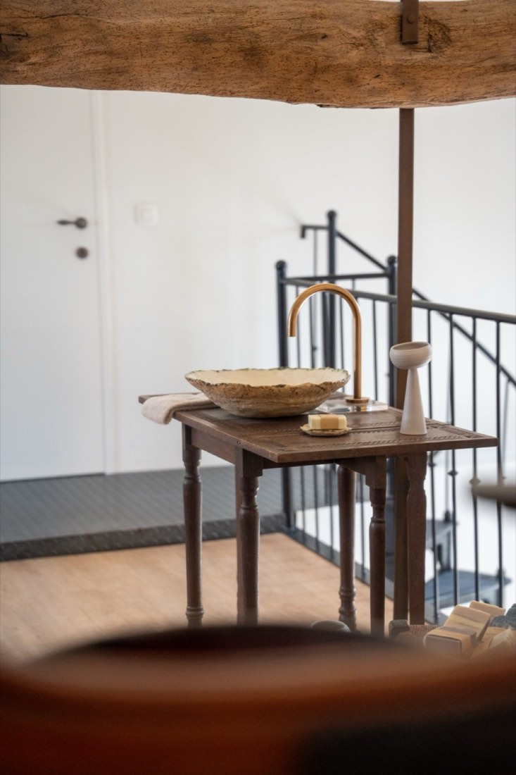 A handmade ceramic washbasin bowl on a wooden side table