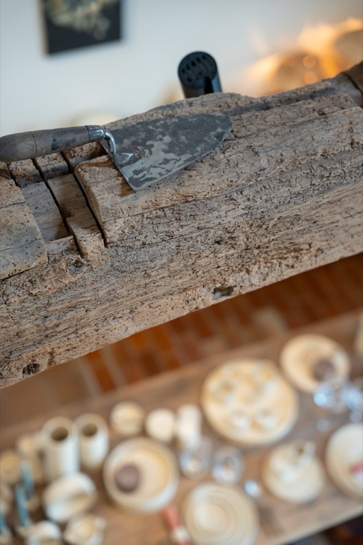 Detail of a weathered wooden beam with a trowel, ceramics in the background